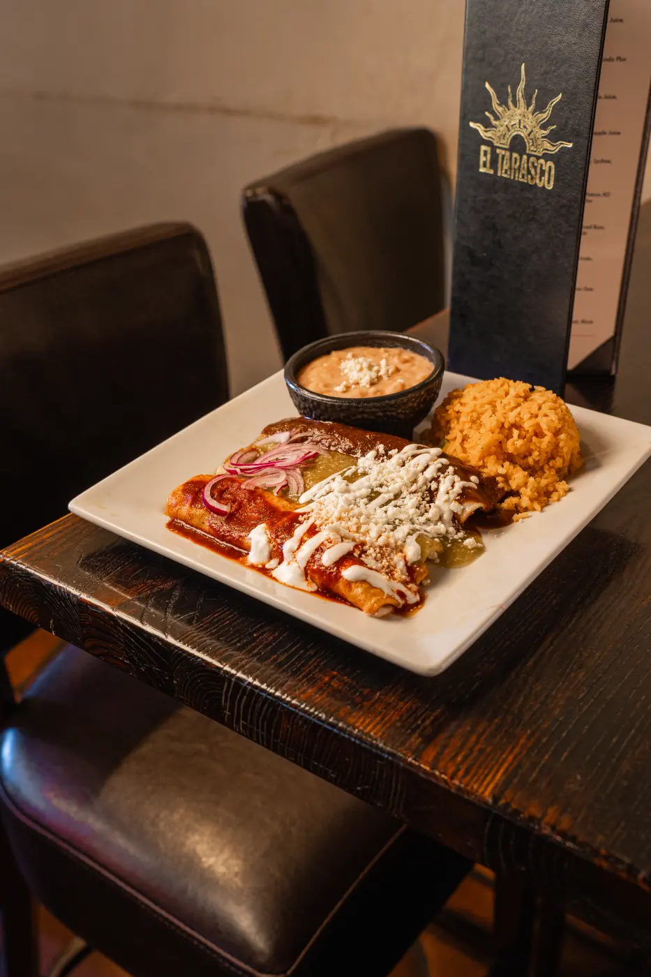 An enchiladas plate with red and green sauce, crema and cotija, served with Mexican rice and beans