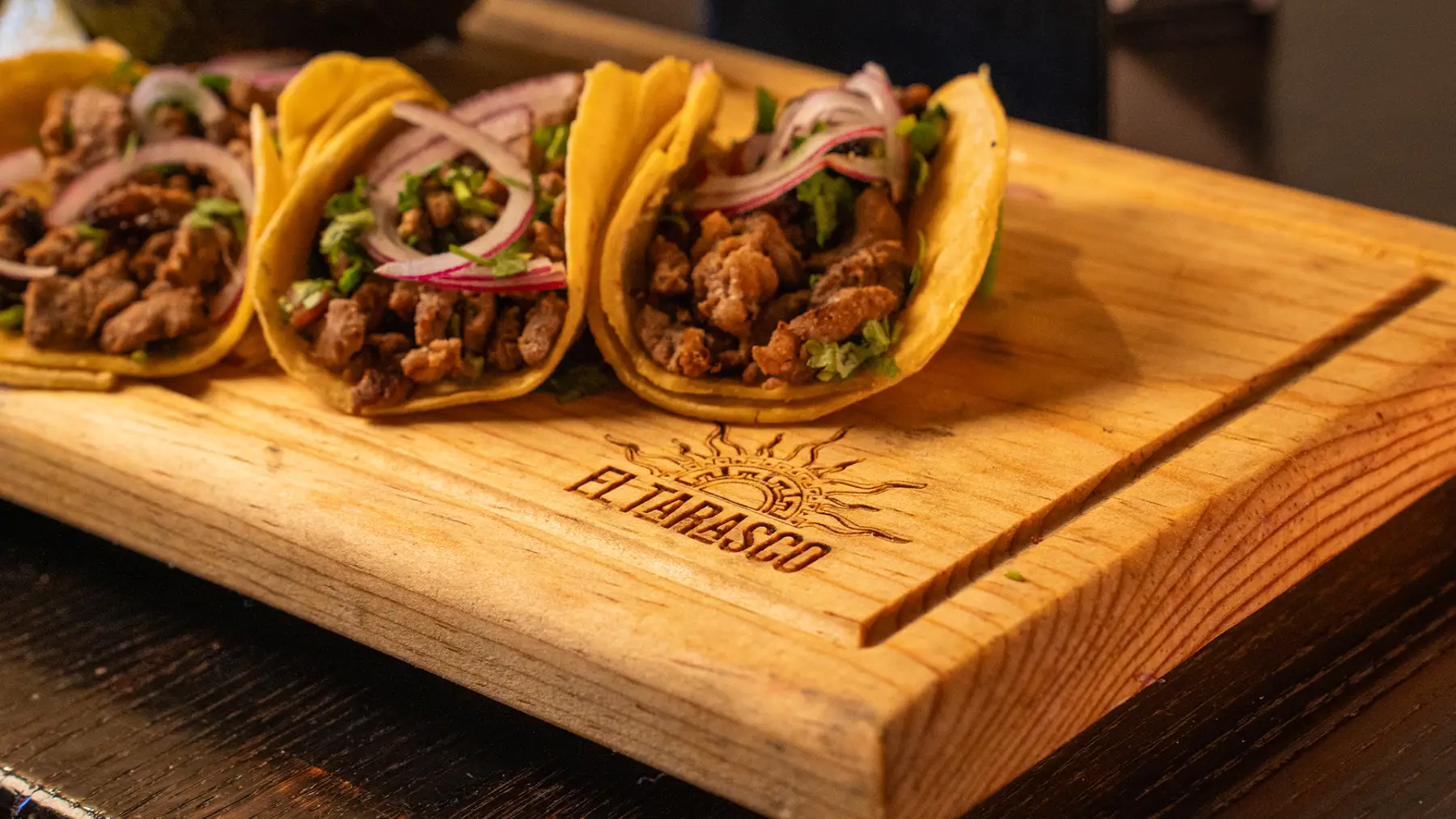 A close look at three carne asada street tacos topped with cilantro and pickled red onion